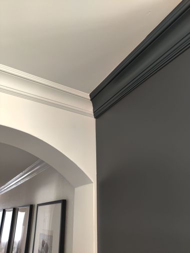 Interior corner with white arched wall molding and a dark gray accent wall near the ceiling.