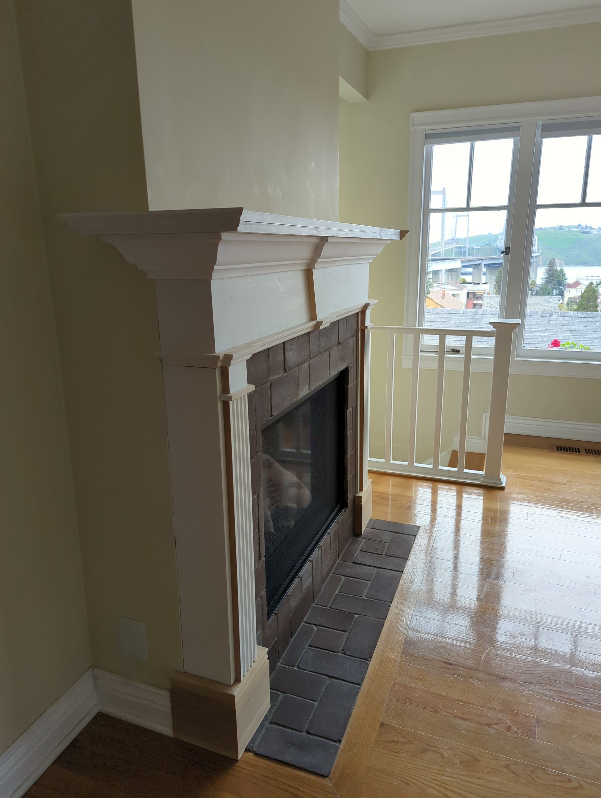 Living room fireplace with white mantel and black tile hearth beside a window and balcony door