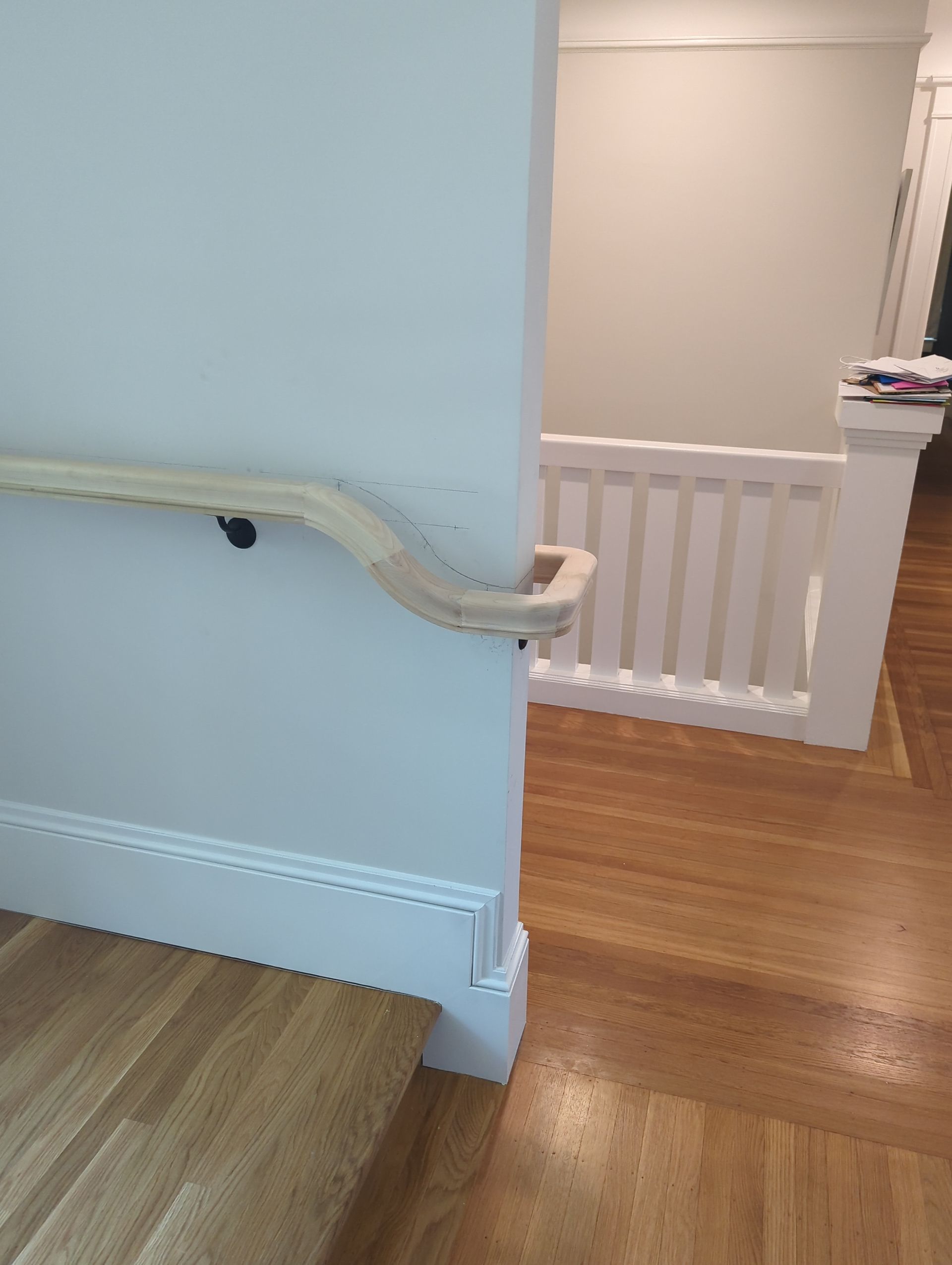 Indoor staircase with white handrail, blue wall, and wood flooring leading to a hallway landing