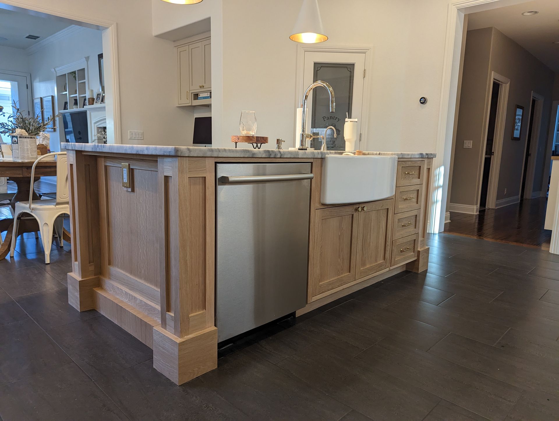 Open kitchen with wood island, stainless dishwasher, and dark hardwood floors in a bright home interior