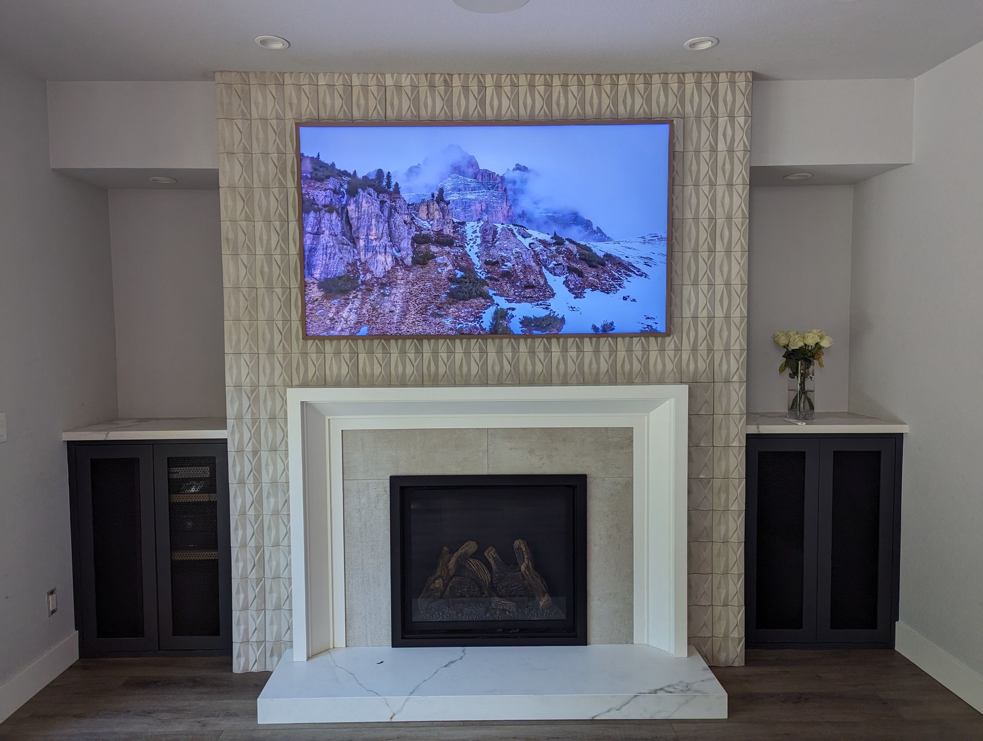 Living room fireplace with mounted TV showing a rocky shoreline scene and matching dark side cabinets