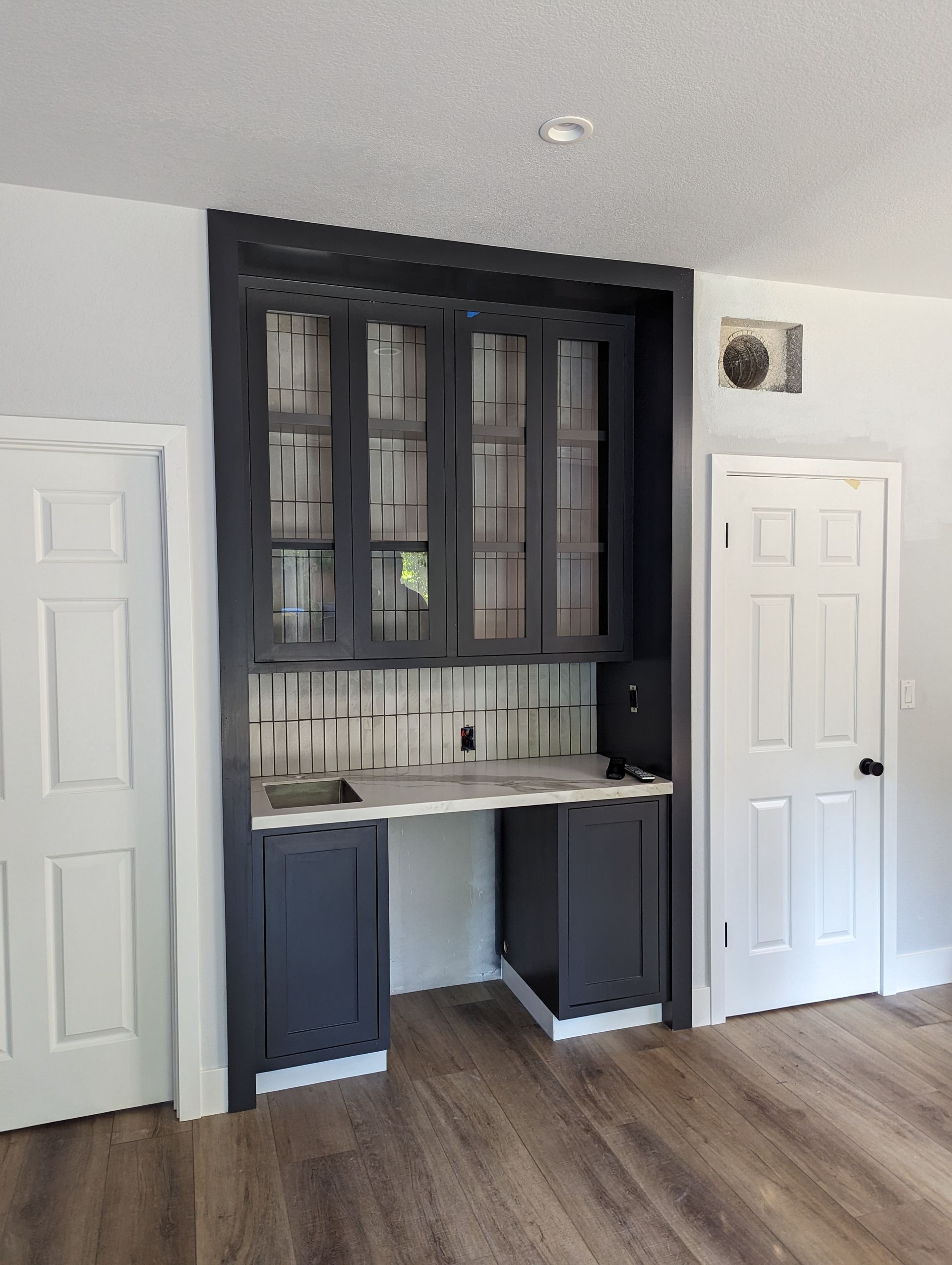 Living room wall with built-in black cabinet, white desk nook, and two white doors on either side