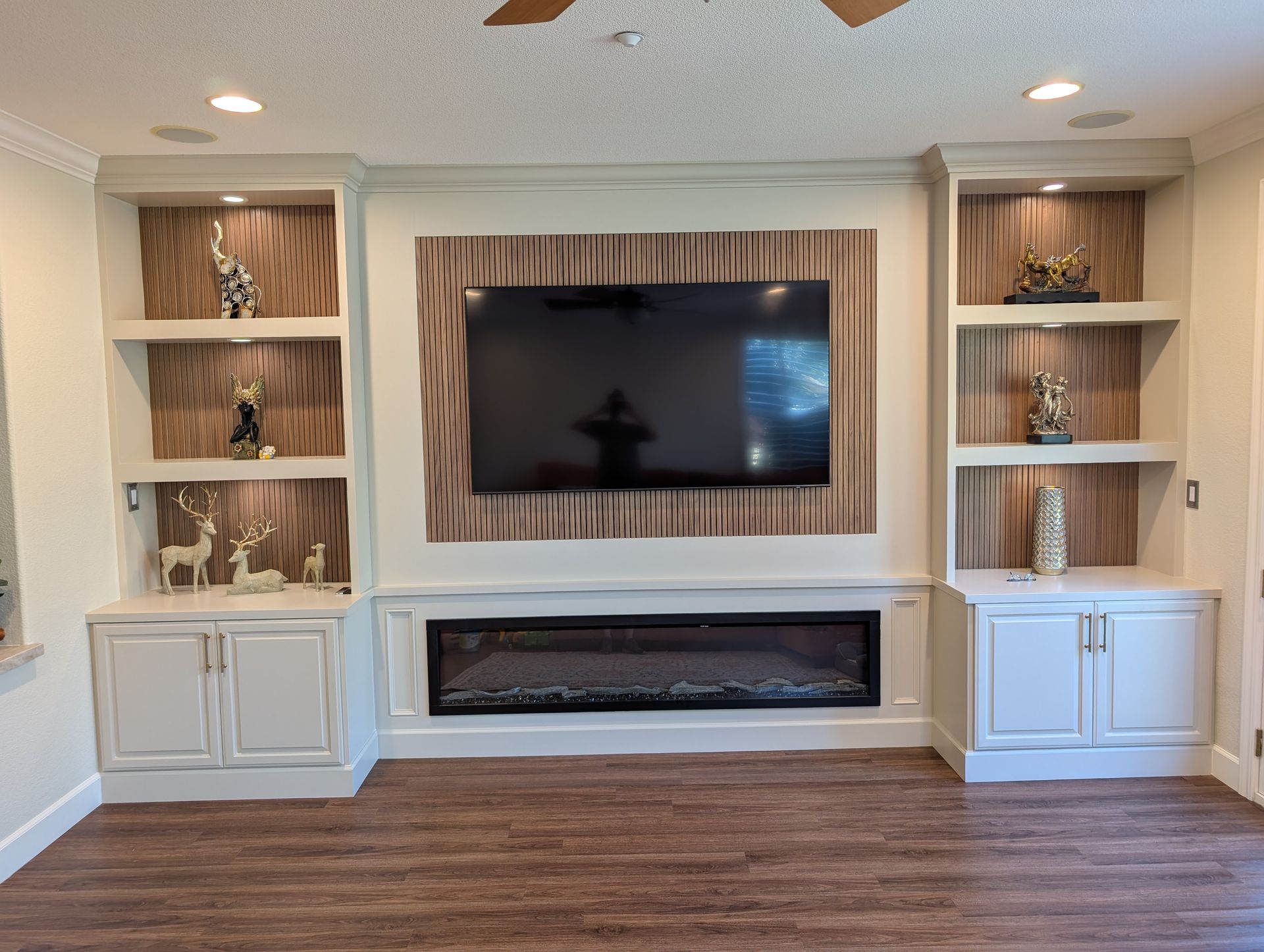 Living room built-ins with a wall-mounted TV, fireplace, and wood flooring