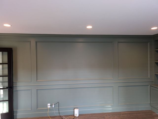 Empty gray paneled room with recessed ceiling lights and a dark windowed door on the left