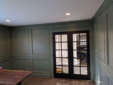 Green paneled room with recessed lights and French doors to a backyard.