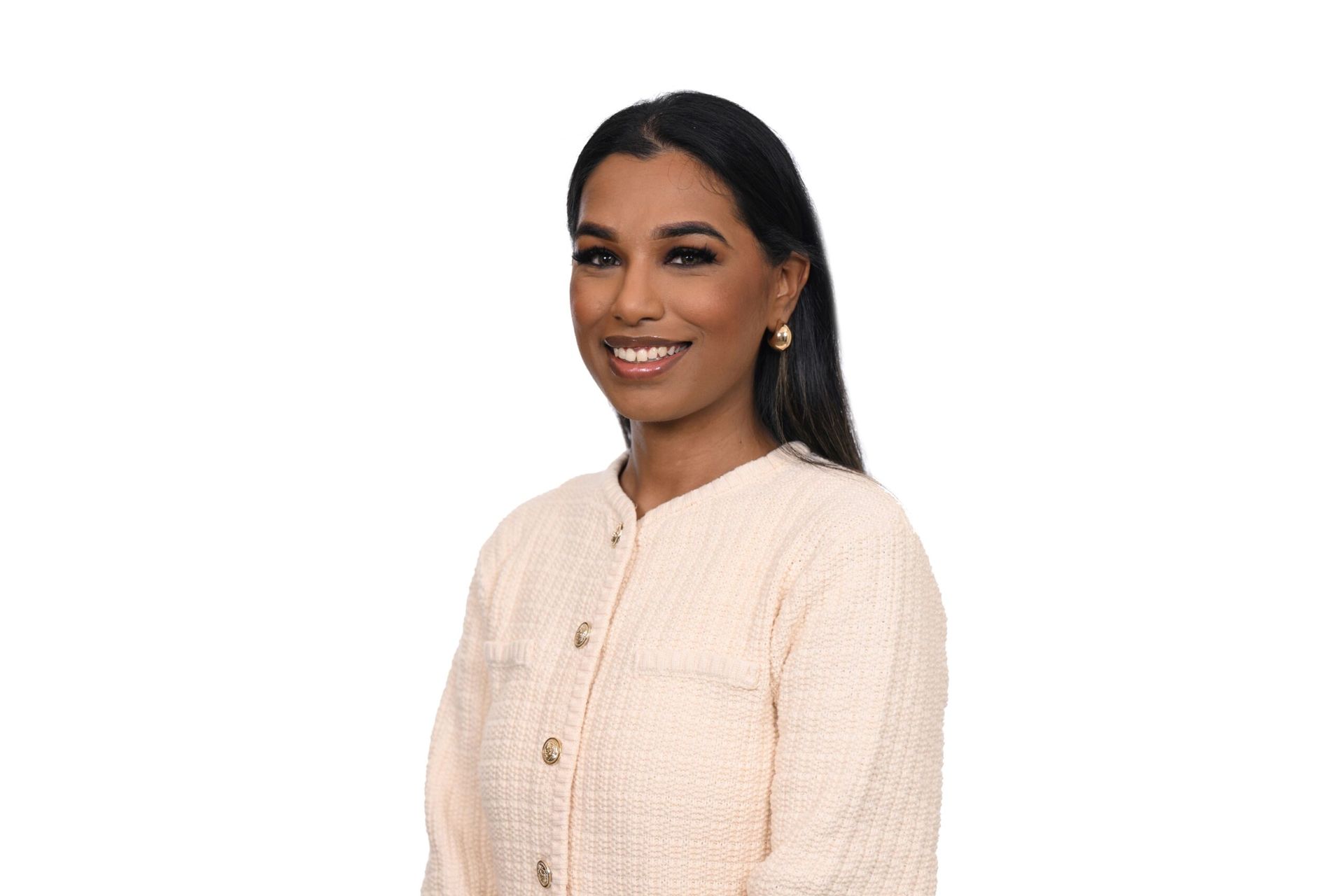 Woman with dark hair smiles, wearing a light pink jacket, standing against a white background.