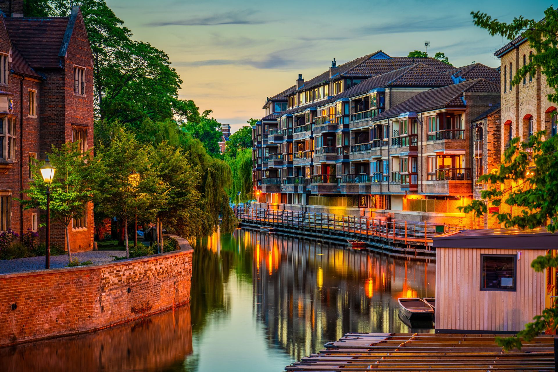 Canal with buildings, trees, and reflections; warm evening light.
