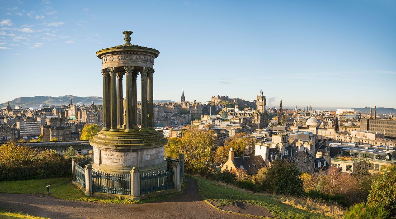 Edinburgh cityscape with the Dugald Stewart Monument in the foreground on a sunny day.