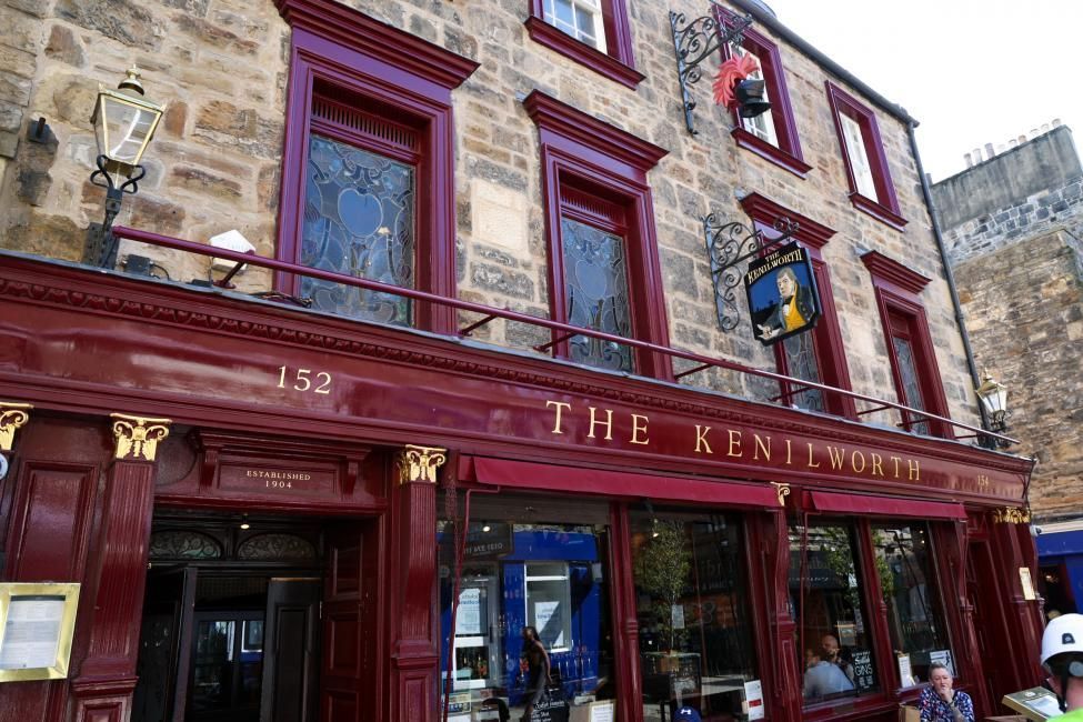 The Kenilworth pub exterior, Edinburgh. Red and gold trim, stone facade, sign with a portrait.