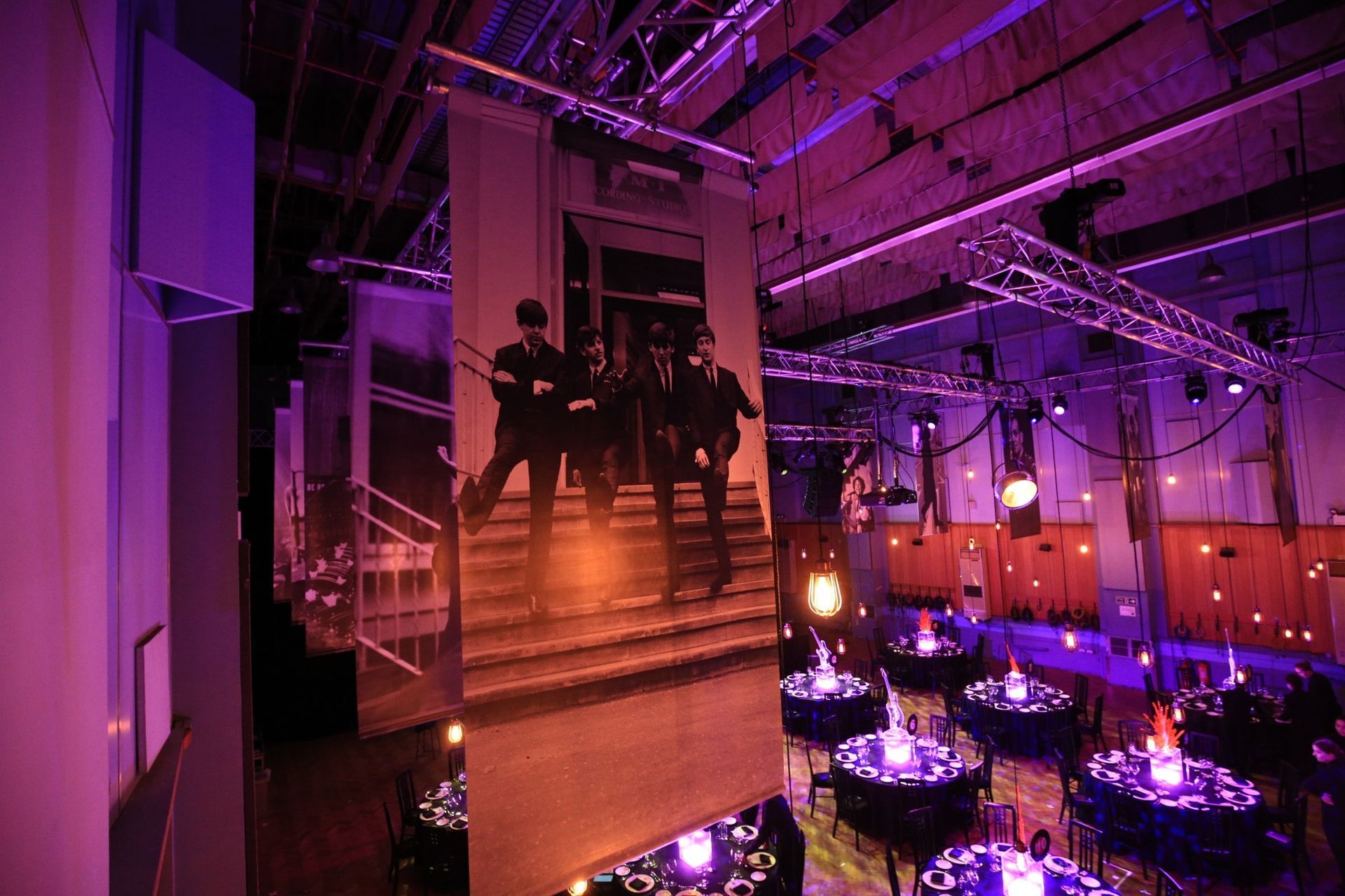 Event space with hanging photo banners; tables set with purple lighting.
