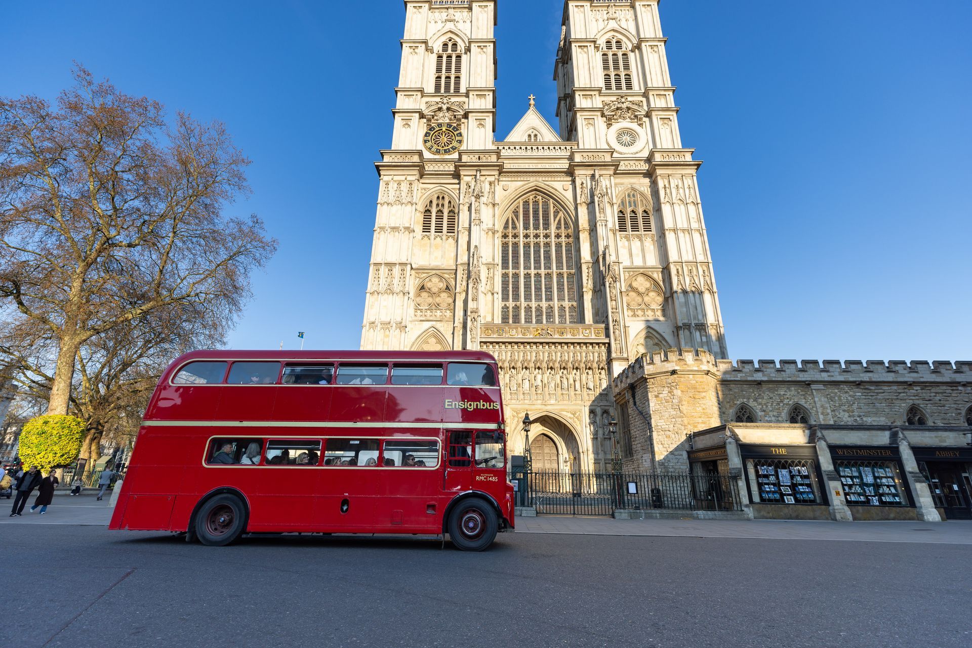 Red double-decker bus in front of Westminster Abbey, London, on a sunny day.
