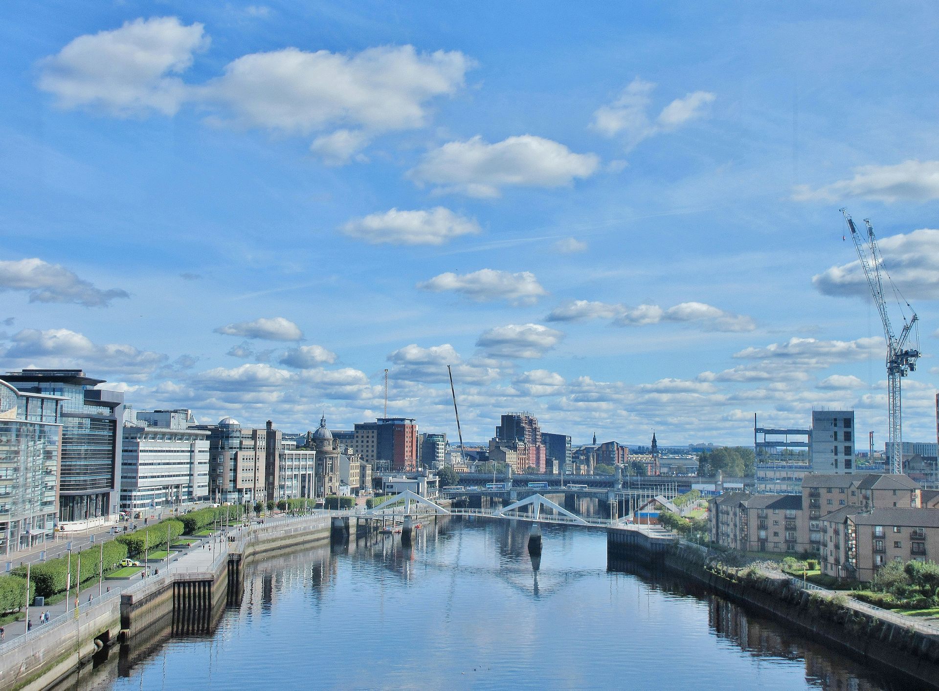 City skyline with a river, blue sky, and scattered clouds.