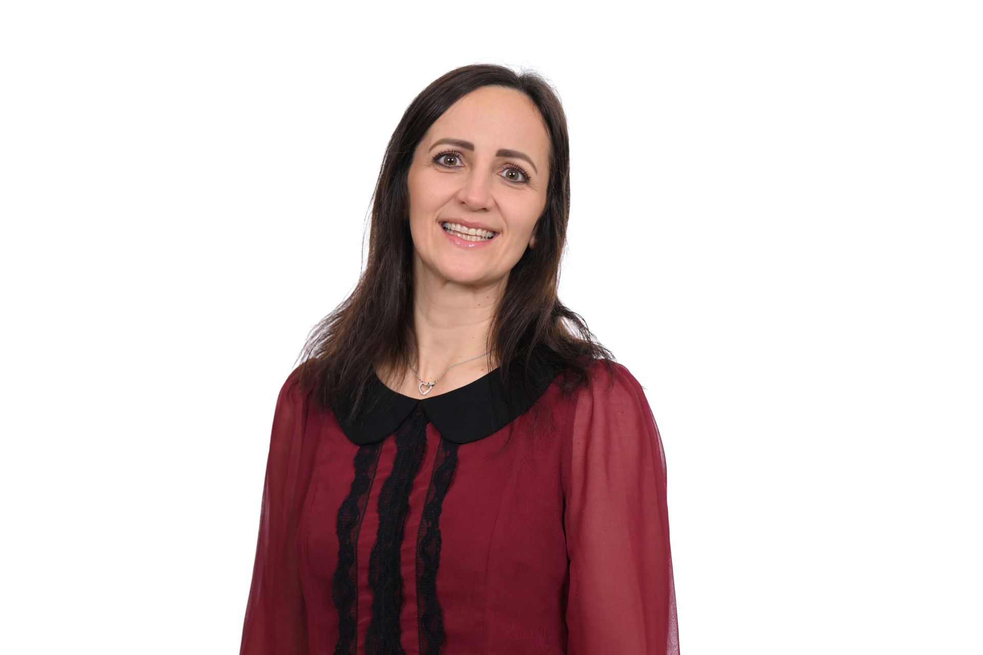Woman with dark hair, smiling, wearing a burgundy top with black collar against white background.