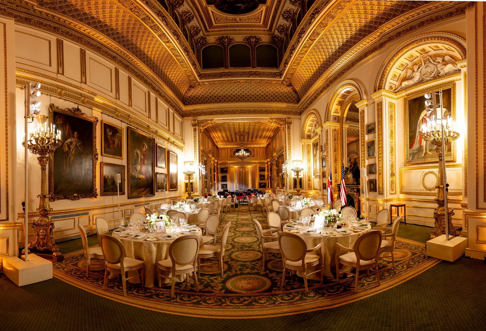 Formal dining hall with ornate gold and white decor, tables set for a banquet.