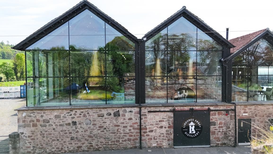 Modern building with glass walls atop stone base; a person stands inside.