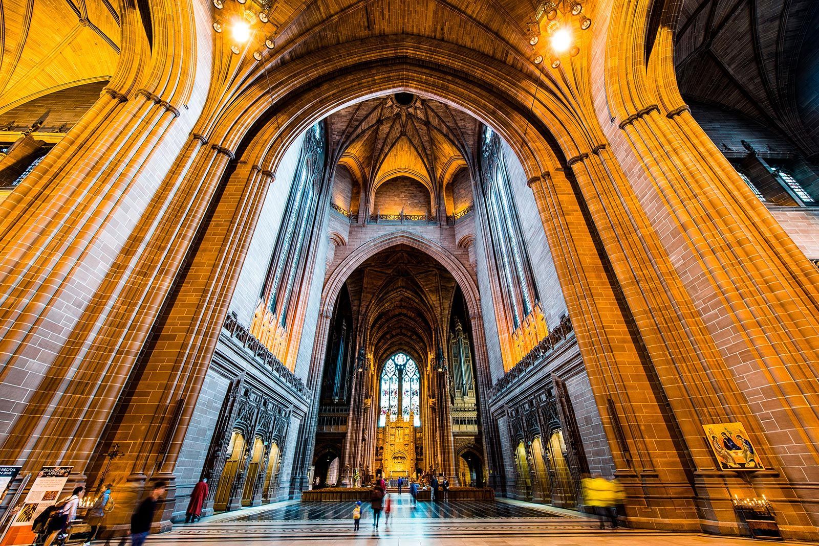 Interior of Liverpool Cathedral, arched ceiling, ornate architecture, people walking towards the altar.