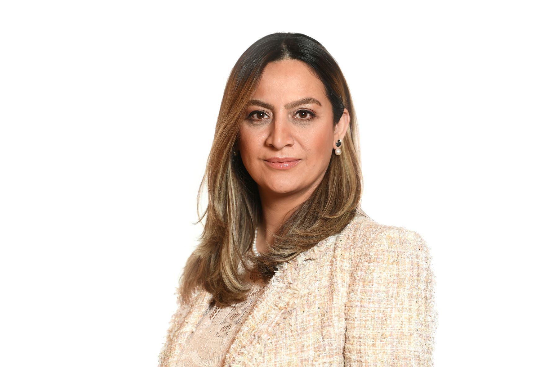 Woman with long brown hair, wearing a white tweed blazer, facing forward with a neutral expression.