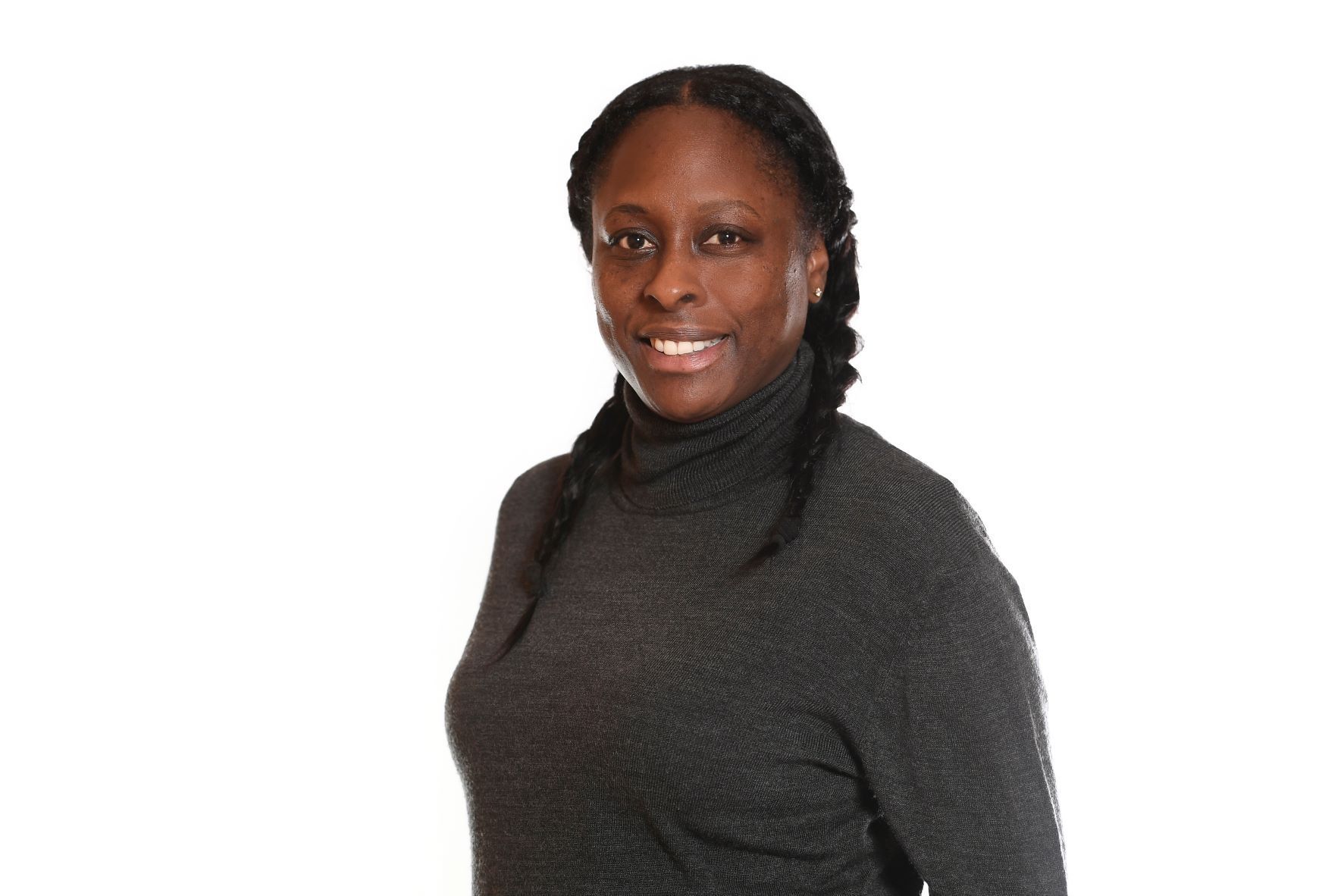 Woman in a black turtleneck smiles, braids on one side, against a white background.