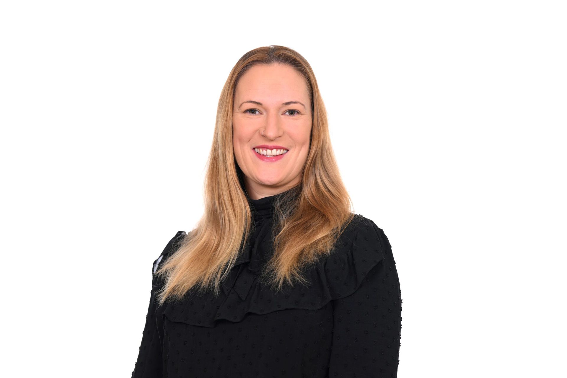 Woman with blonde hair wearing a black top smiling against a white background.