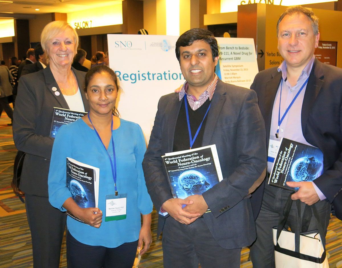 Four people at a conference registration, holding brochures.