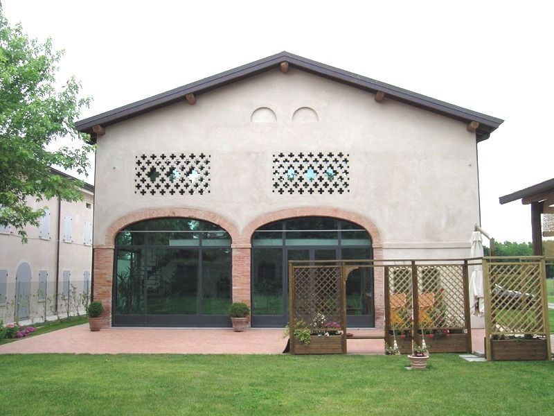Edificio color marrone chiaro con porte ad arco in vetro, ritagli decorativi in ​​pietra, tetto marrone e prato erboso.