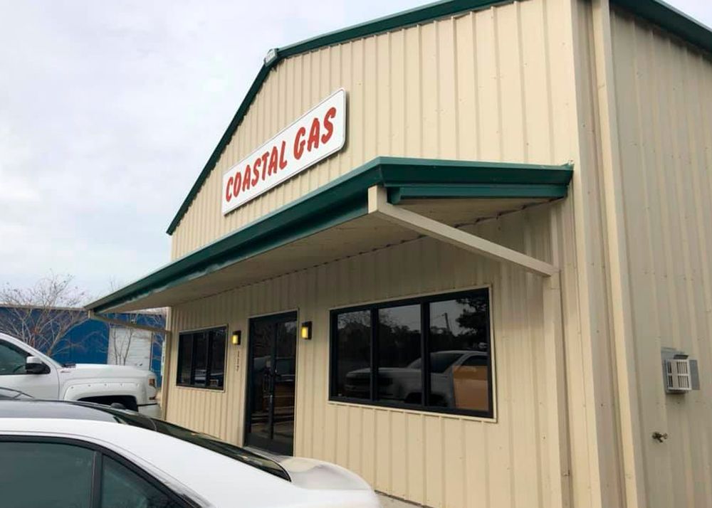 Coastal Gas building with a sign, awning, and cars parked out front.