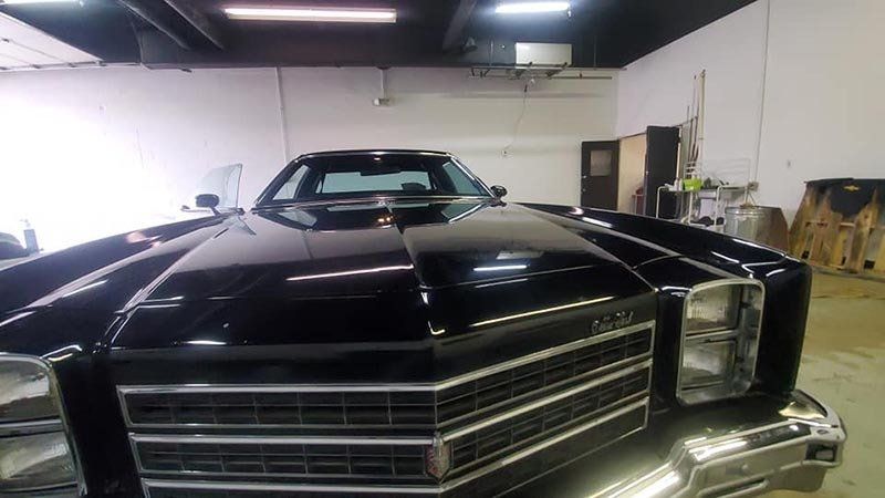 Black classic car with chrome grill in an indoor garage.