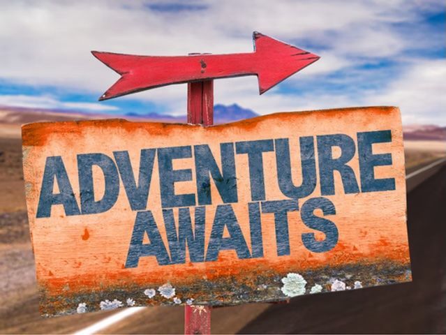 Wooden sign reading “ADVENTURE AWAITS” with a red arrow pointing right against a cloudy sky