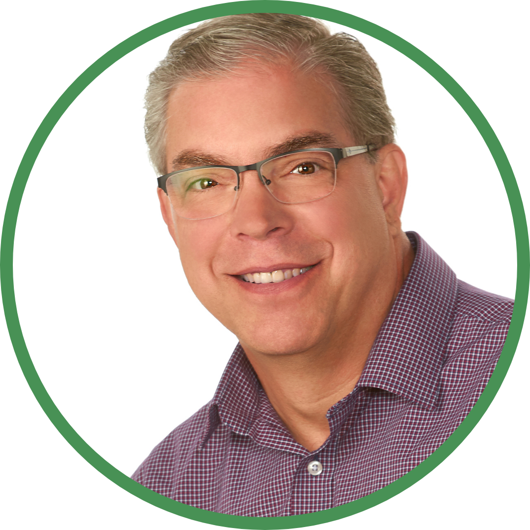 Smiling man with glasses in a purple checkered shirt, framed by a green circle.