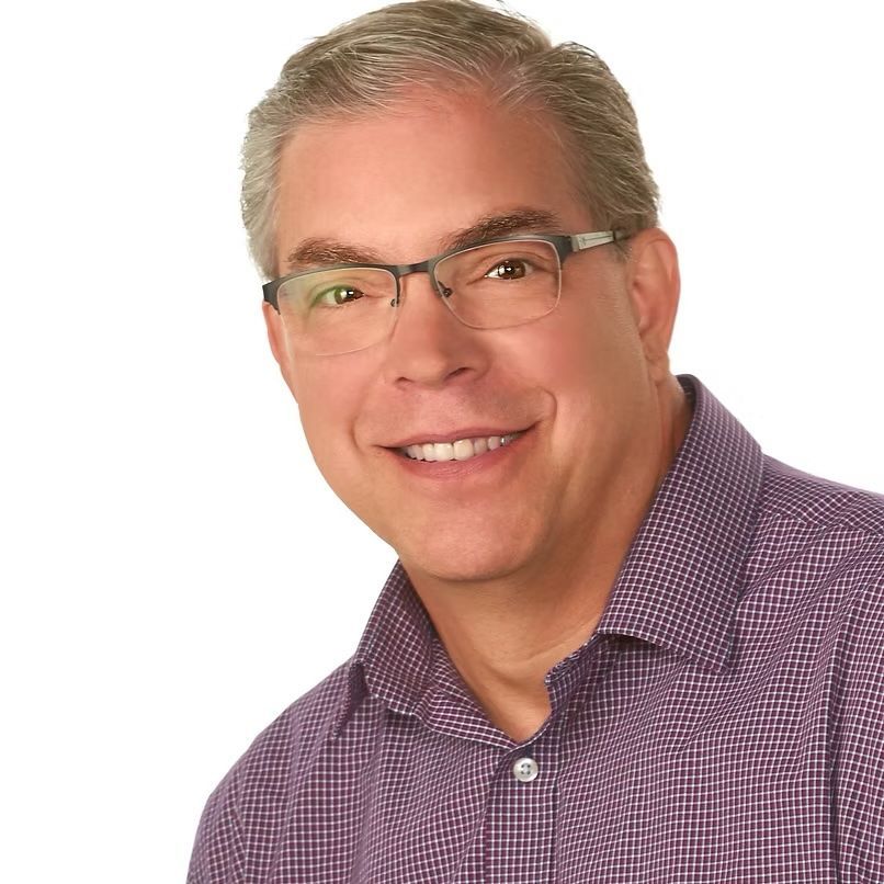 Smiling man in glasses wearing a purple checkered shirt on a white background