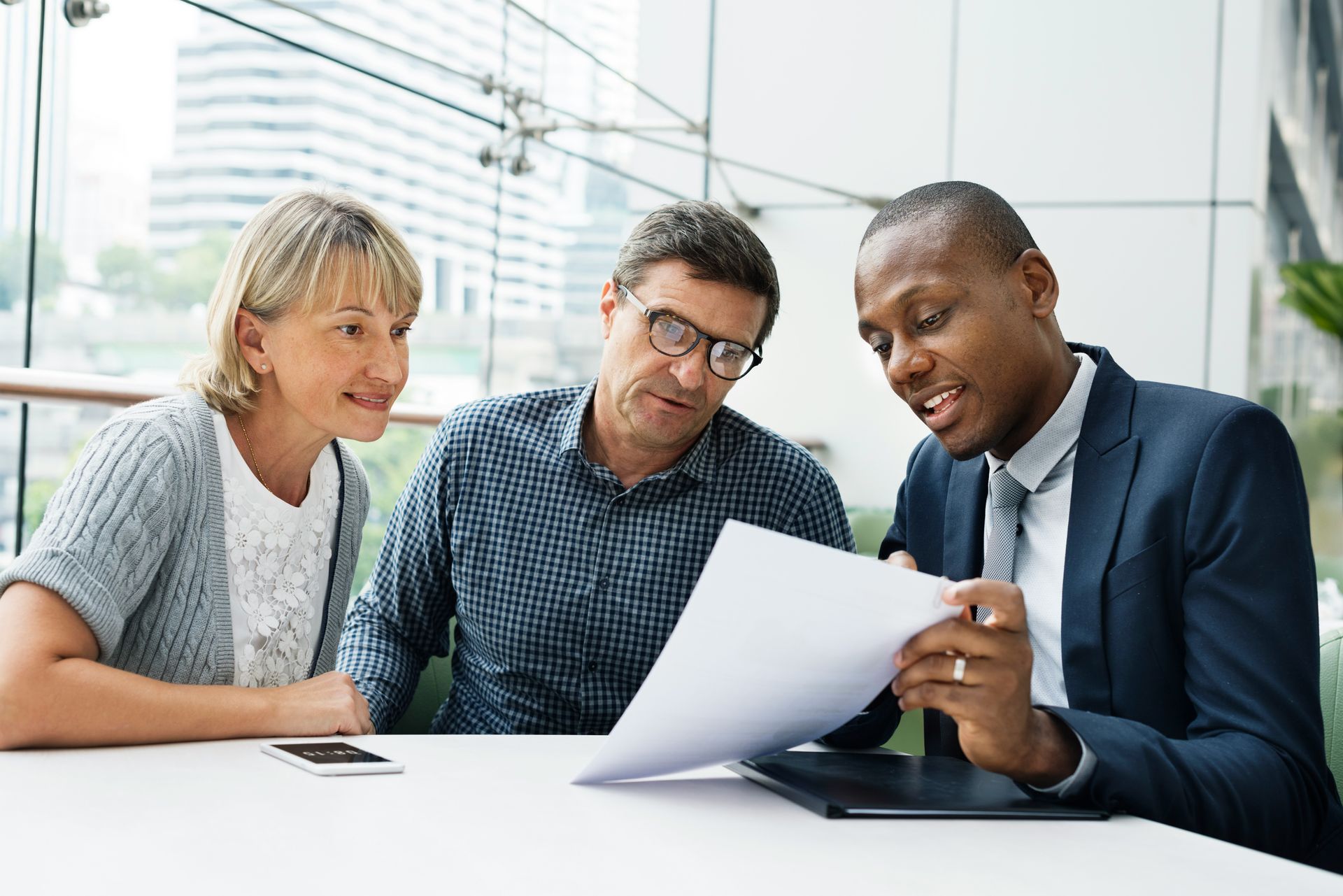 Three colleagues reviewing a document together in a bright office.