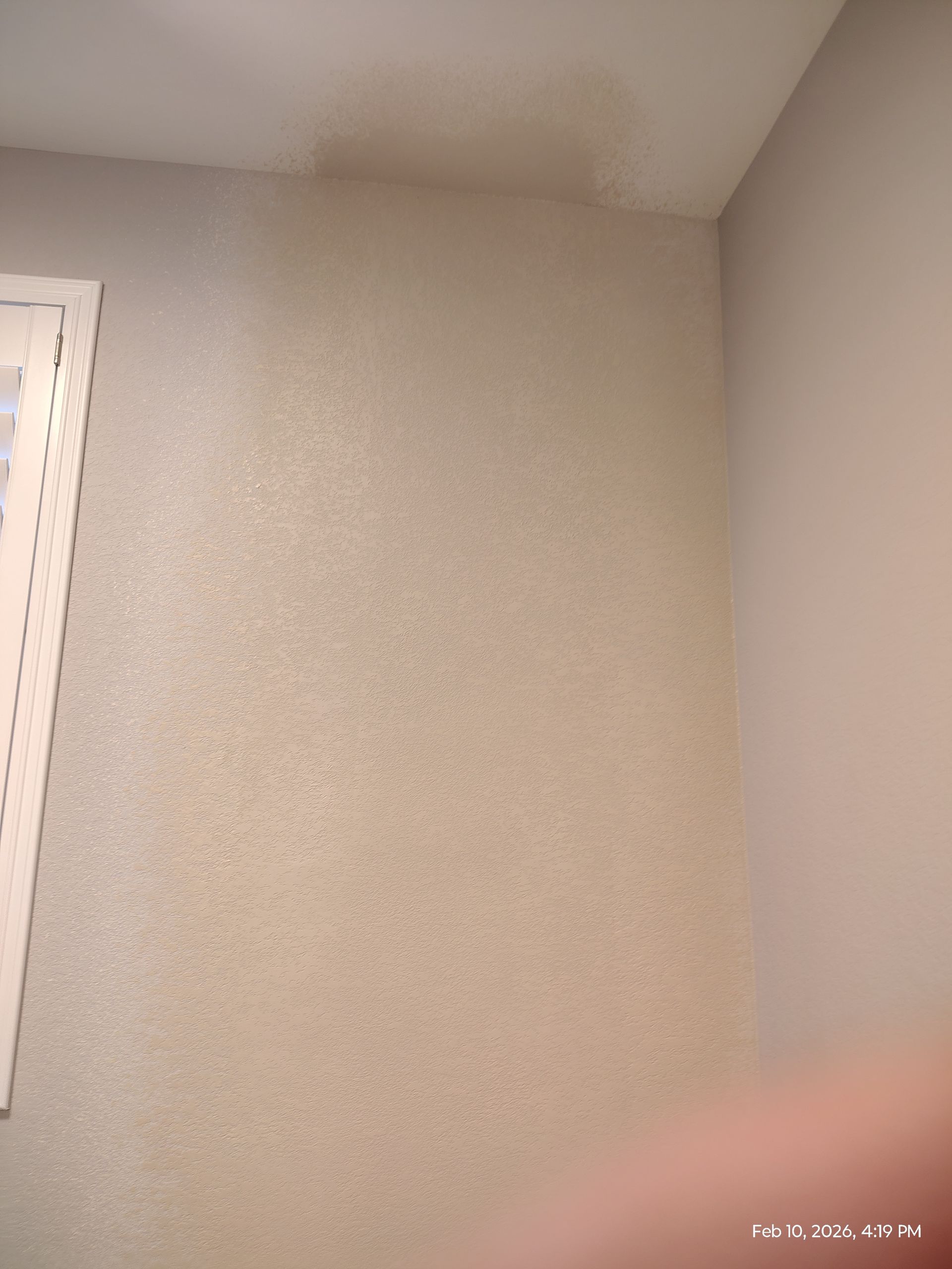 Empty beige textured wall corner with a small window edge on the left.