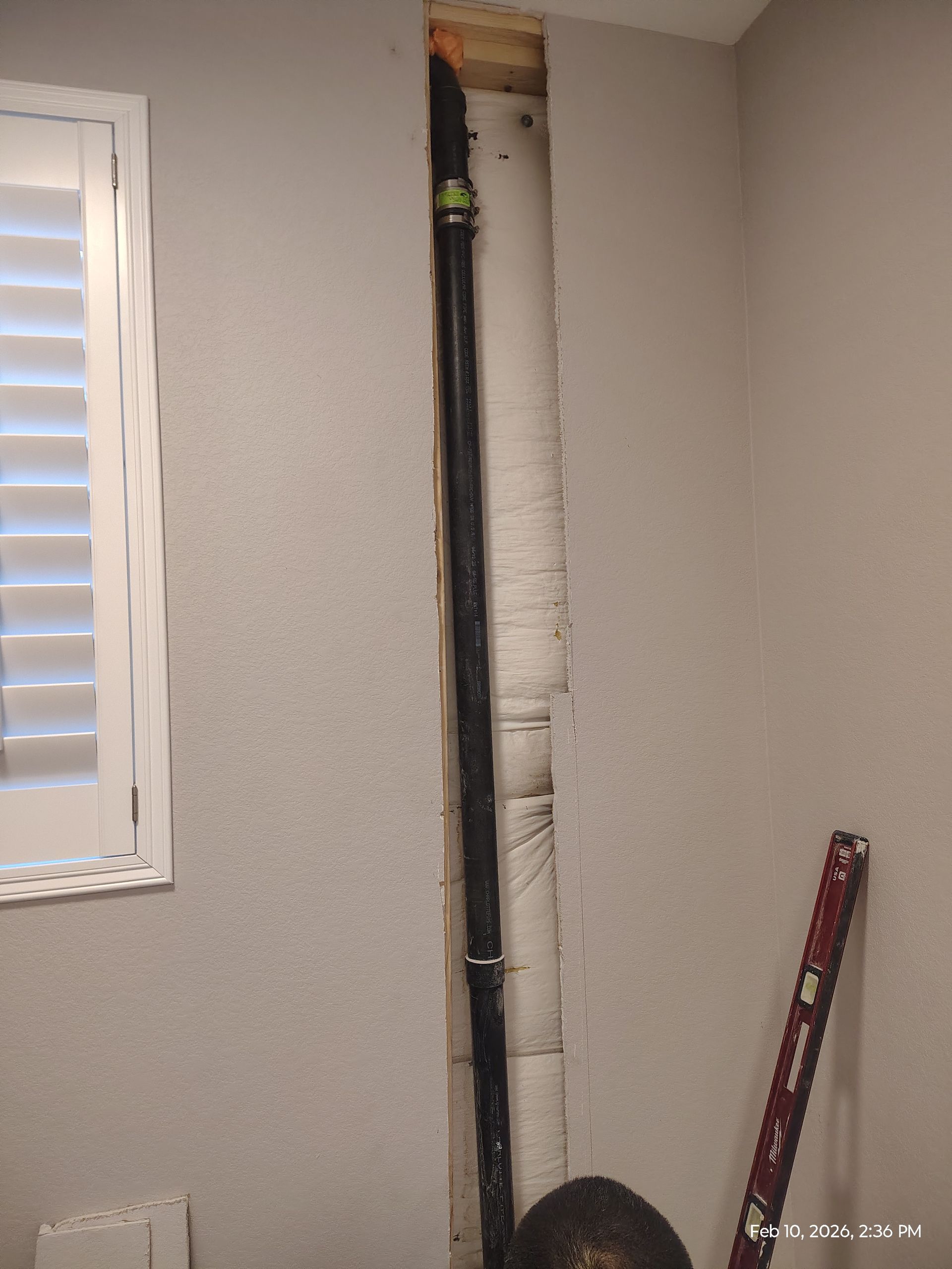 Interior wall with a narrow vertical cut exposing insulation and a ladder leaning nearby