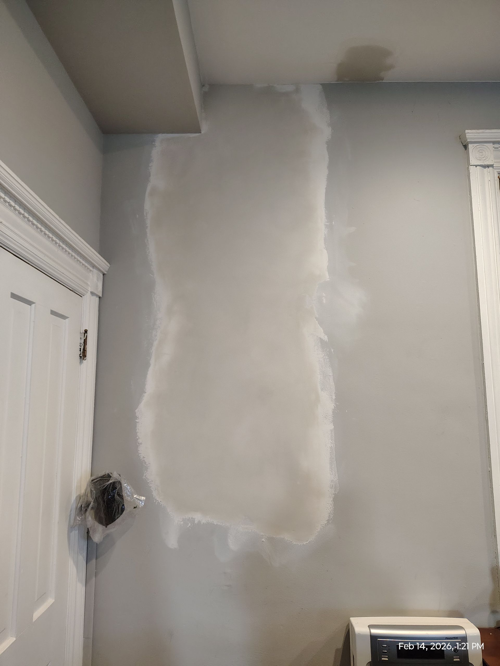 Partially patched drywall on a gray interior wall beside a white door frame