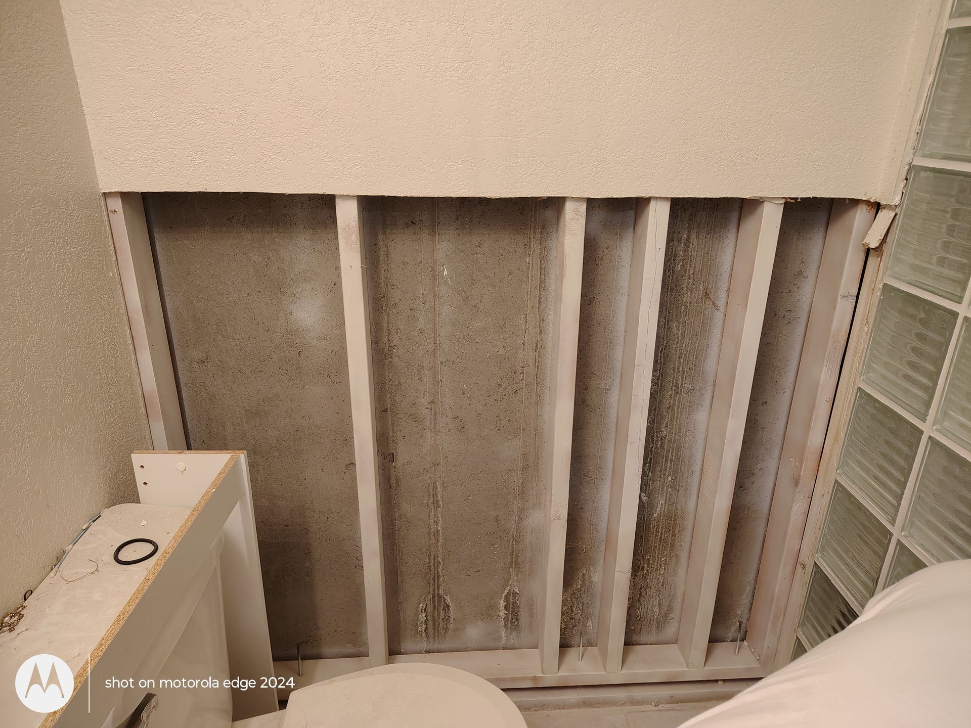 Dirty wall vent with vertical slats, next to a shelf and part of a white air purifier.
