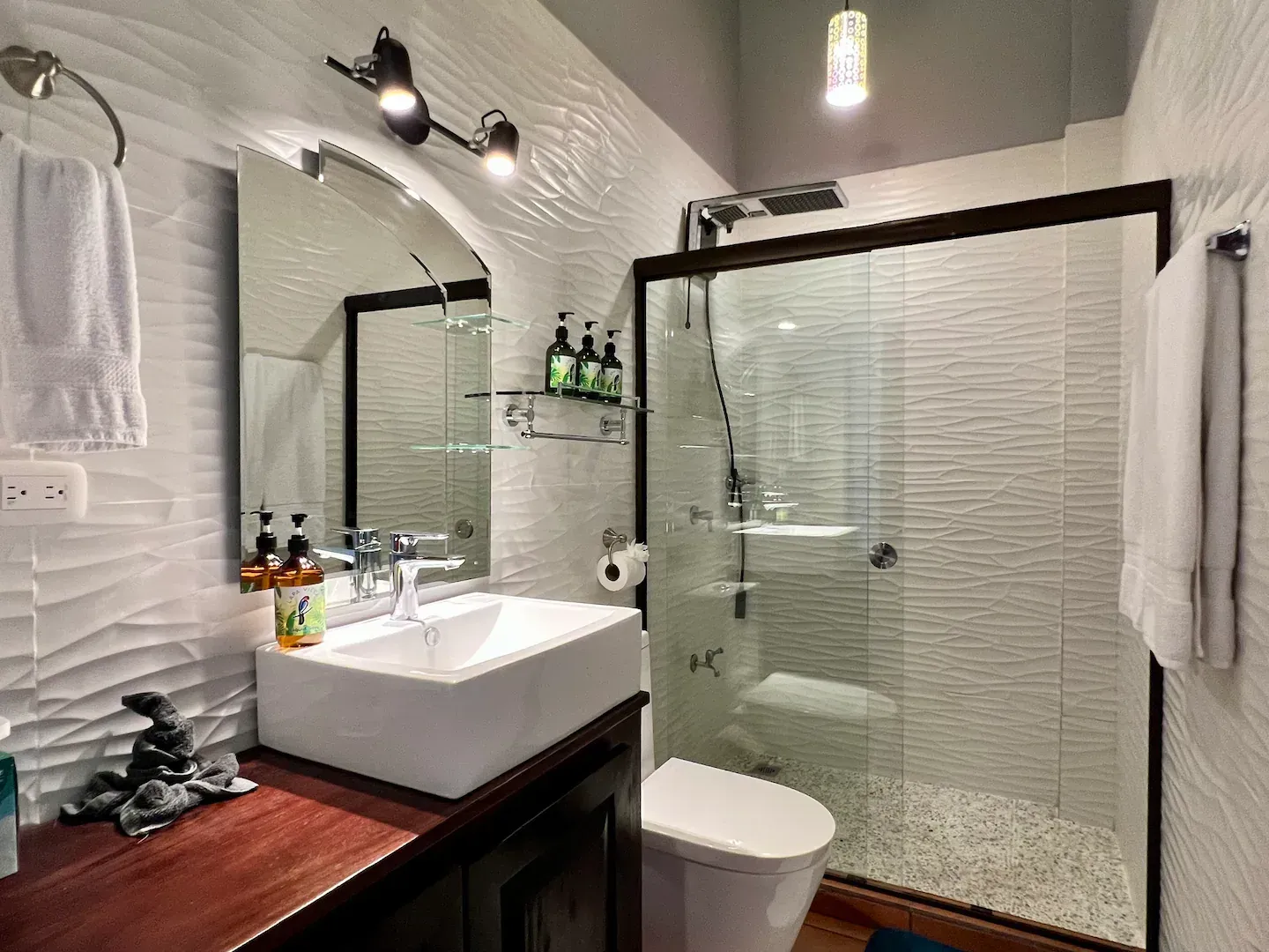 A bathroom with a sink , toilet , shower and mirror.