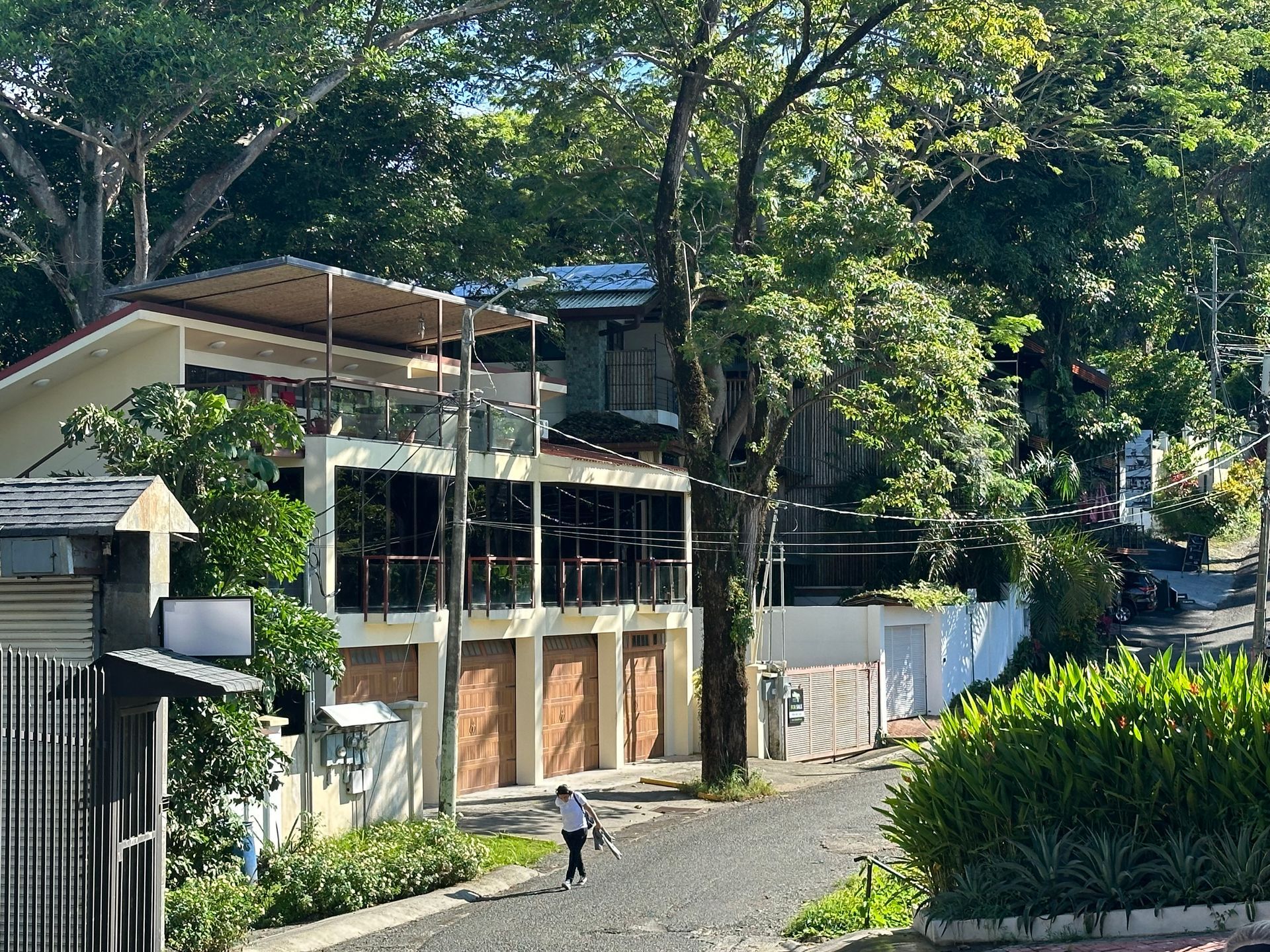 A man is walking down a street in front of a house