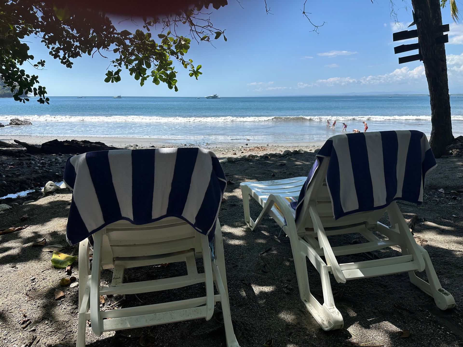 Two chairs on a beach with a blue and white striped towel on them