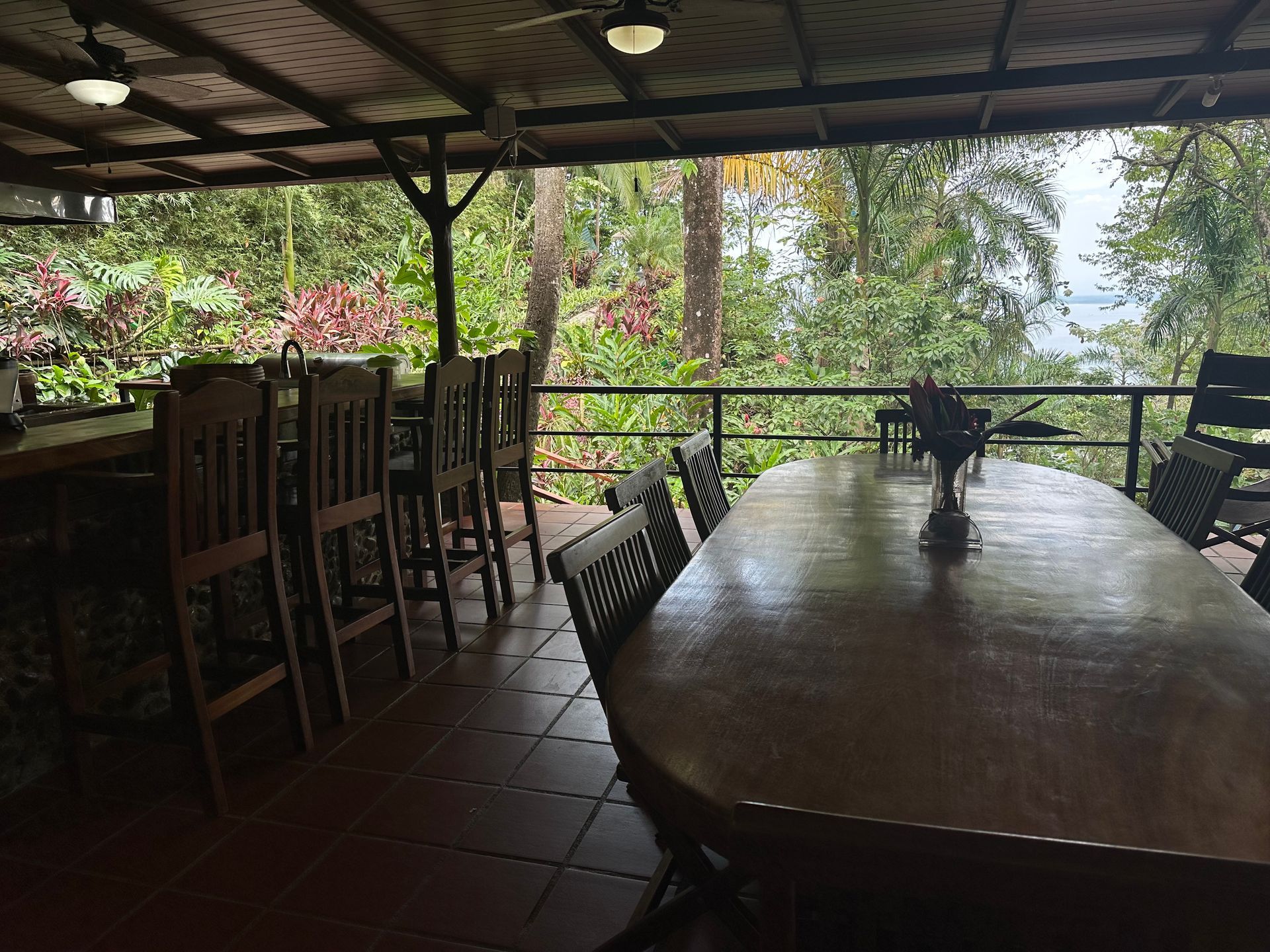 A long wooden table with chairs in a room with trees in the background