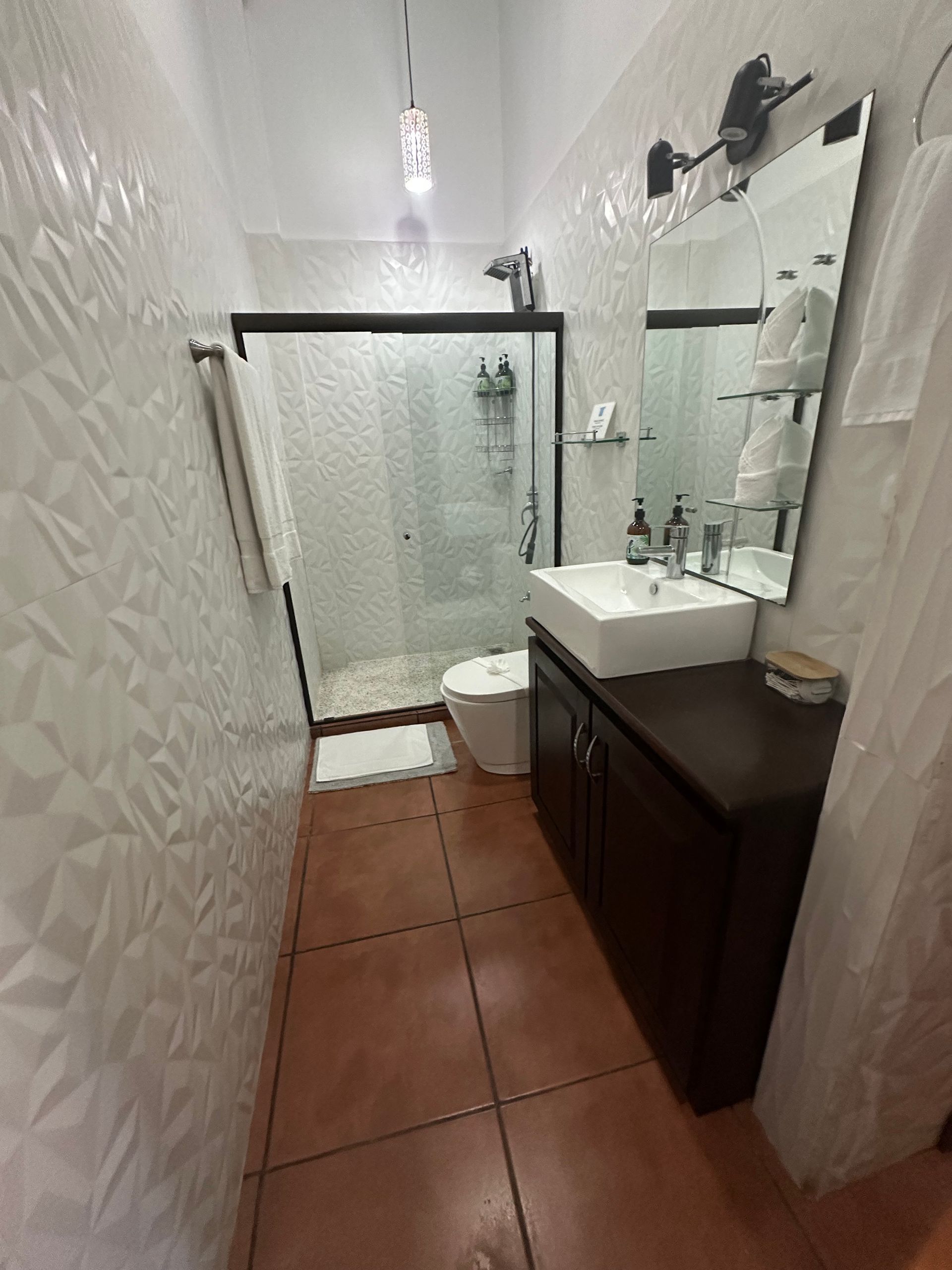 A bathroom with a sink , toilet , shower and mirror.