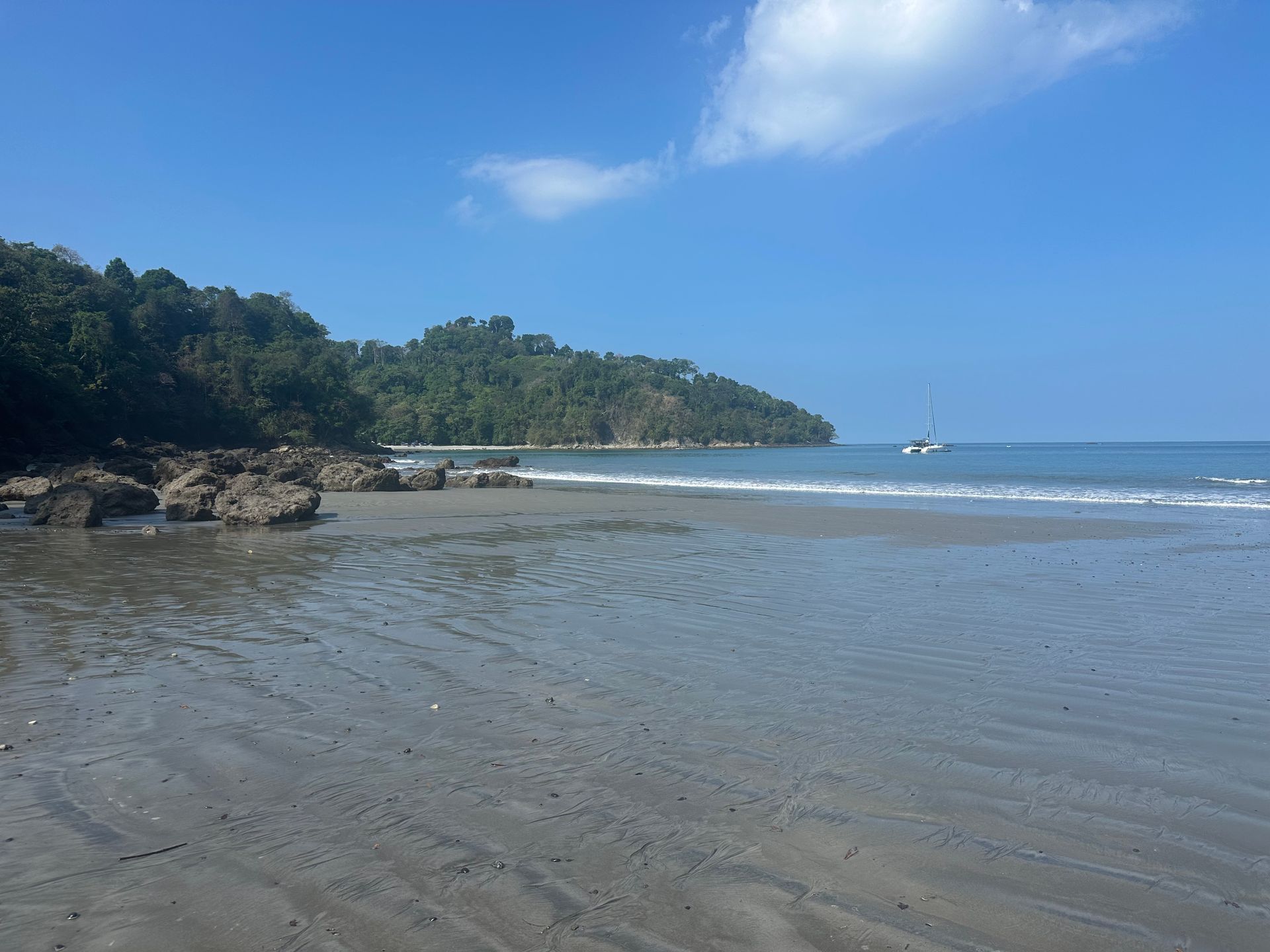 A beach with a boat in the distance on a sunny day