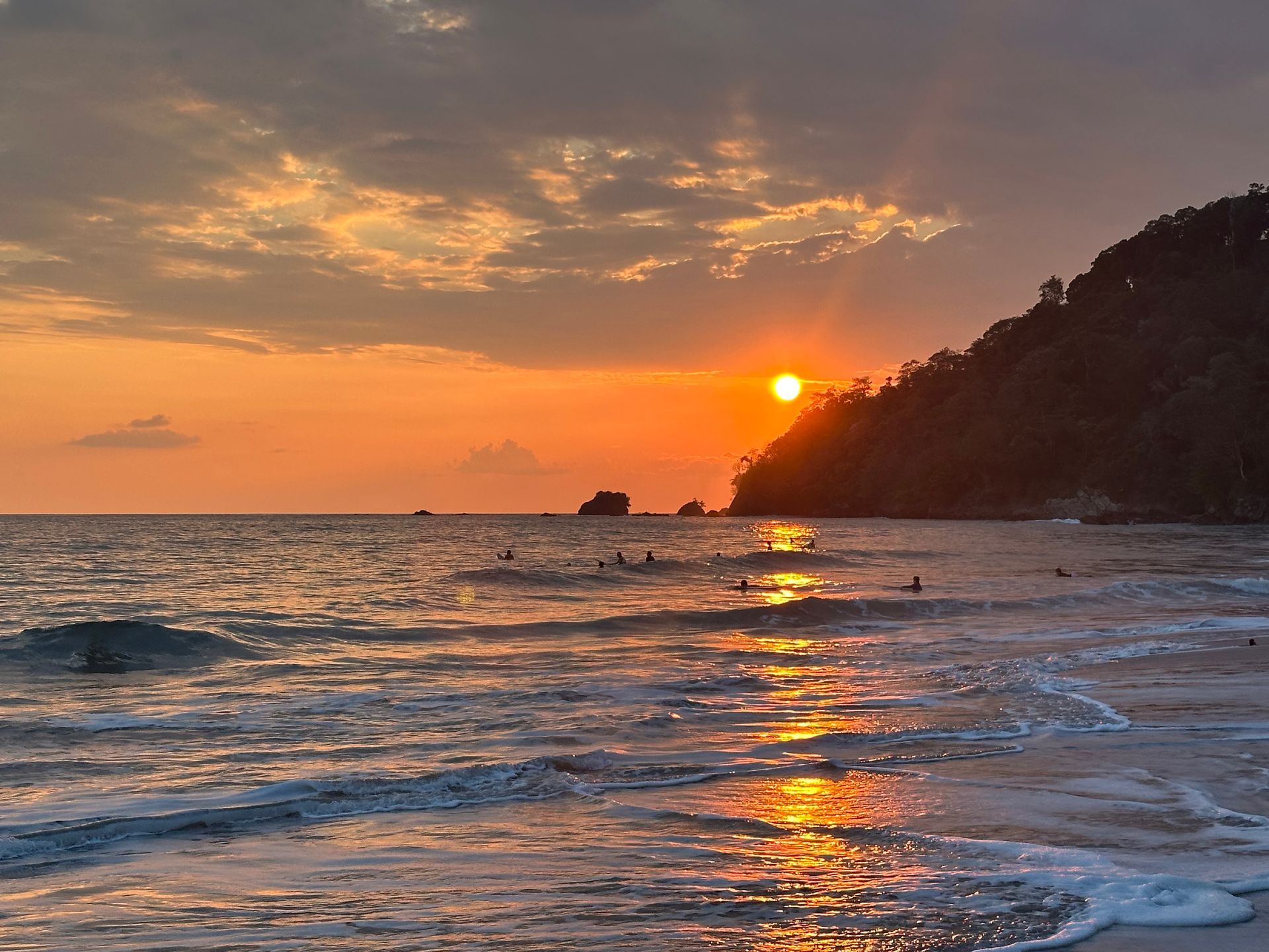 The sun is setting over the ocean on a cloudy day.
