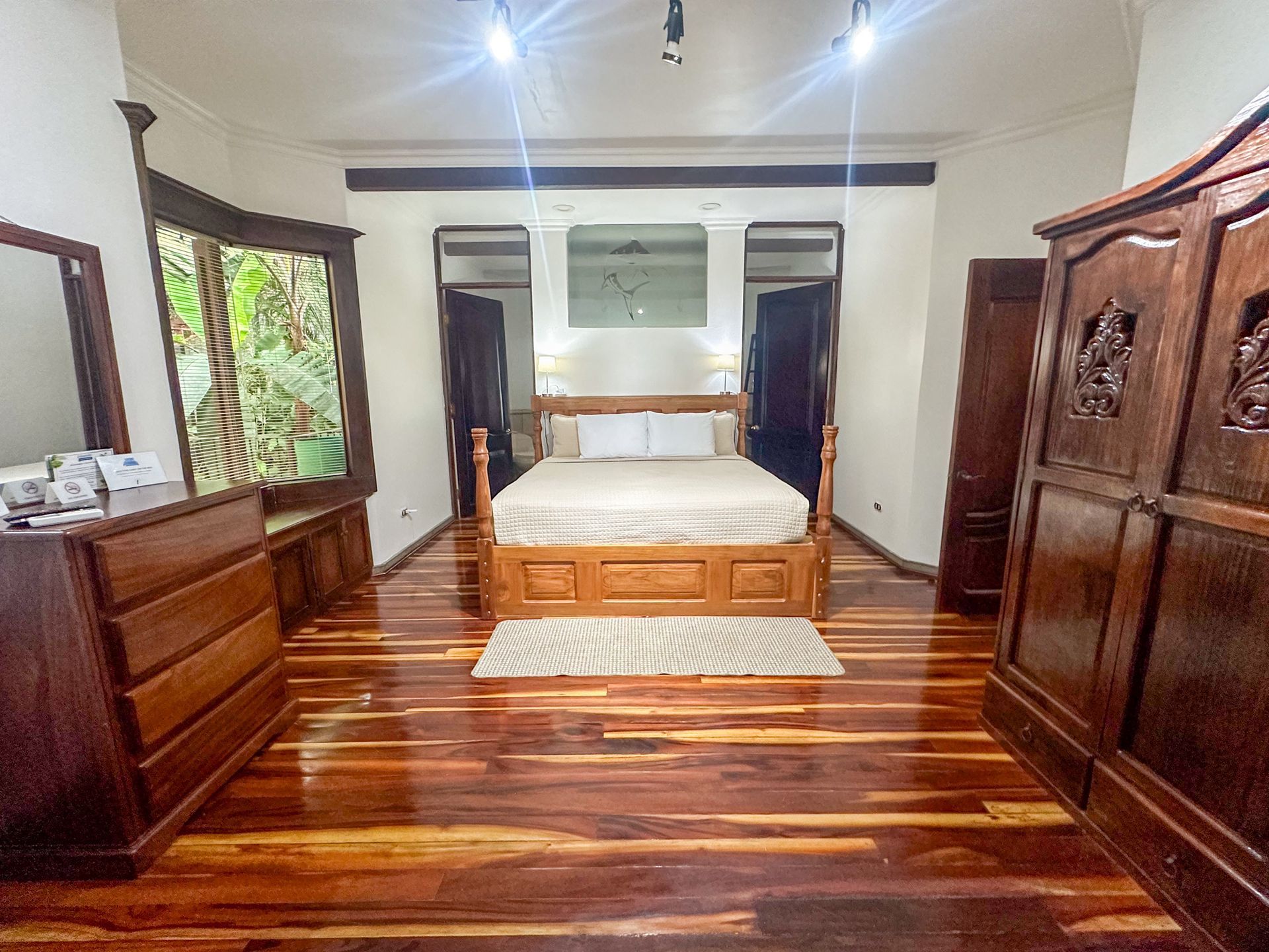A bedroom with a bed , dresser , mirror and wardrobe.