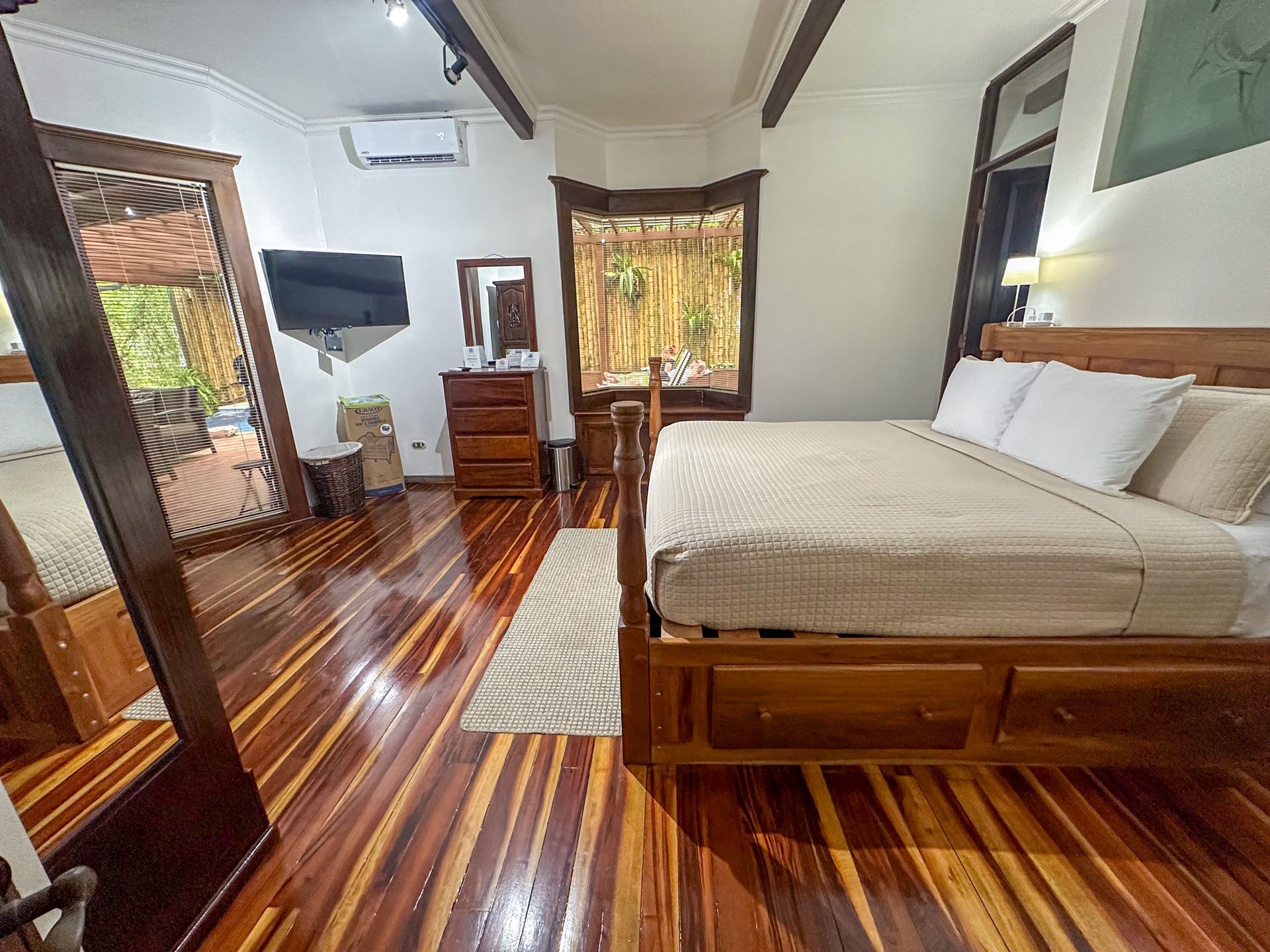 A bedroom with a king size bed , dresser , mirror and television.