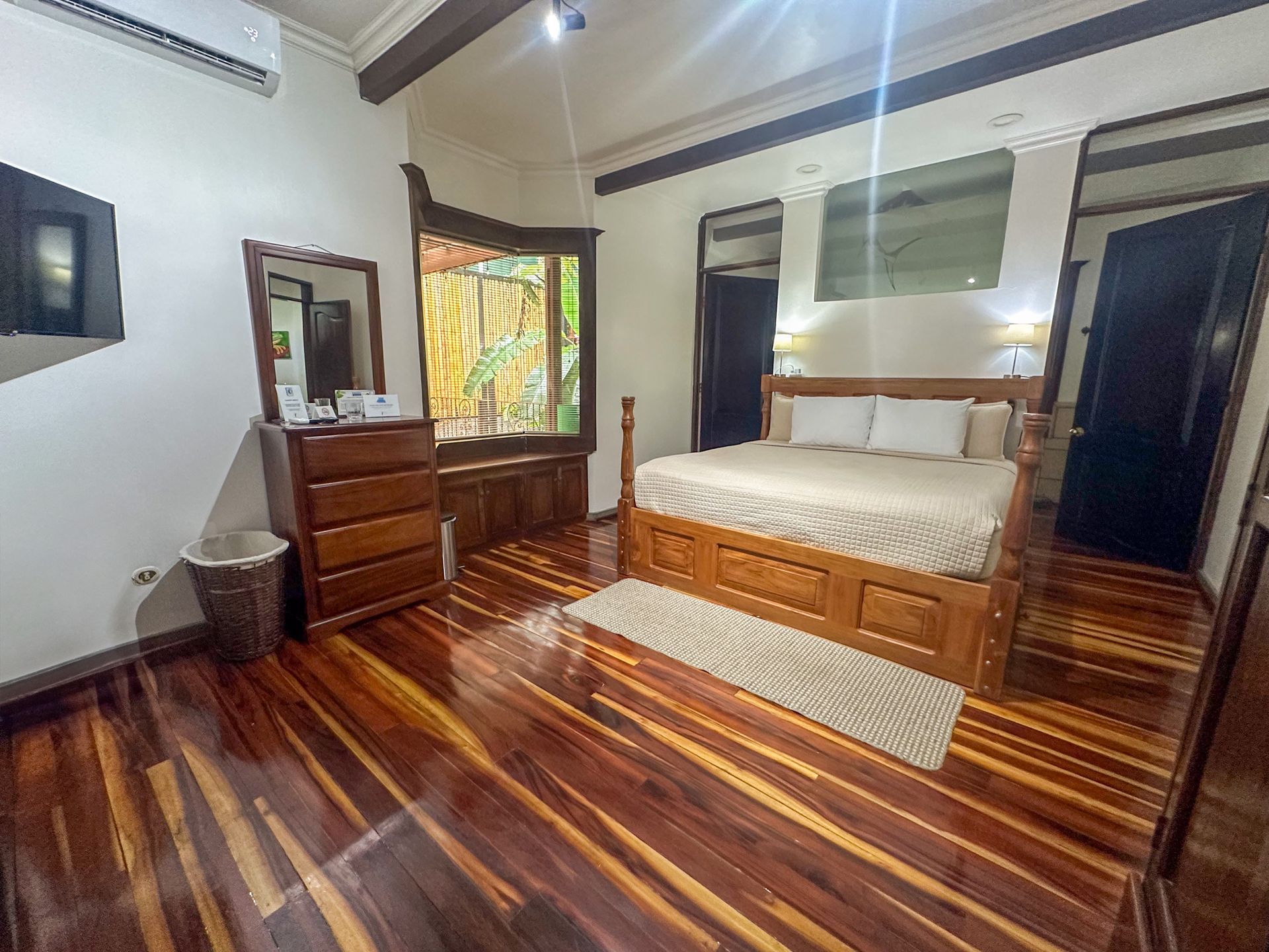 A bedroom with a large bed , dresser , mirror and television.