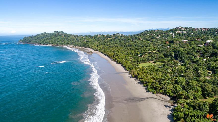 An aerial view of a beach surrounded by trees and a body of water.