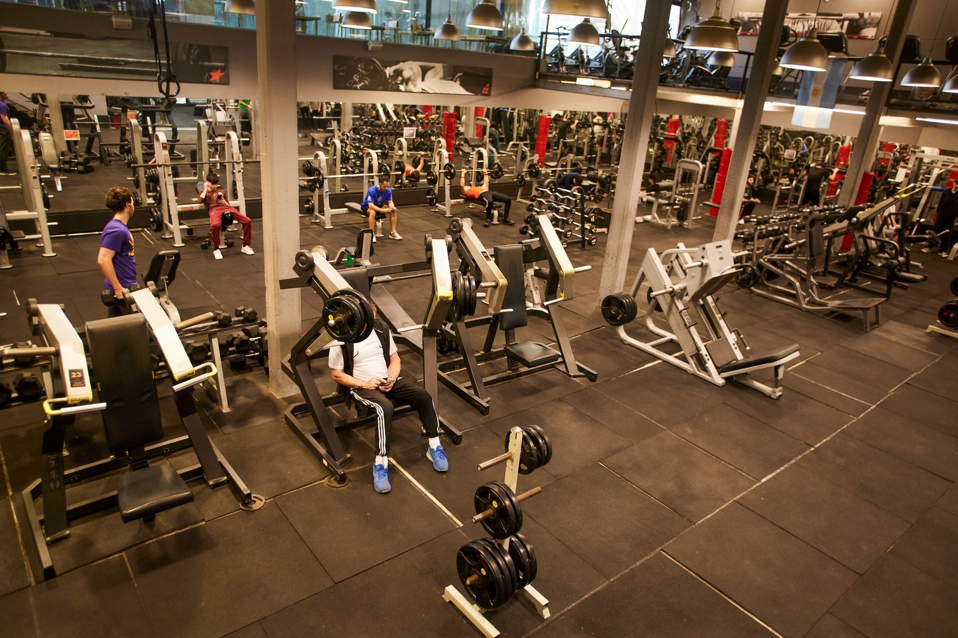 Dos mujeres en cintas de correr en un gimnasio con un letrero que dice 