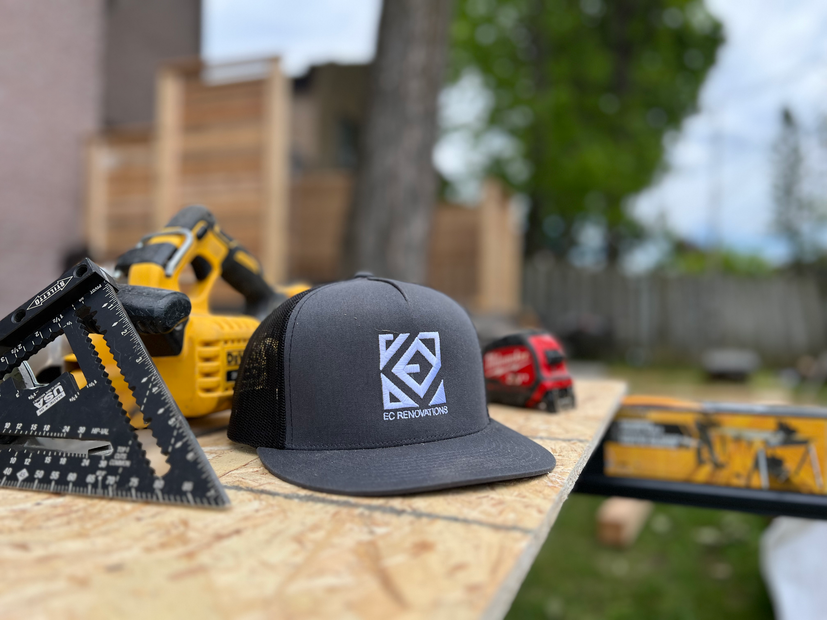 Gray cap on a wooden table with construction tools, including a yellow drill and a black carpenter’s square.