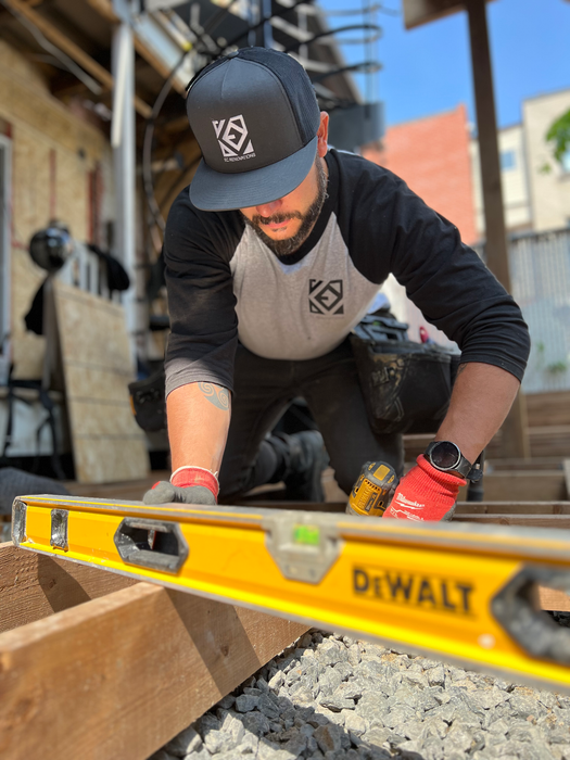 Worker leveling wood with a DeWalt spirit level at a construction site.