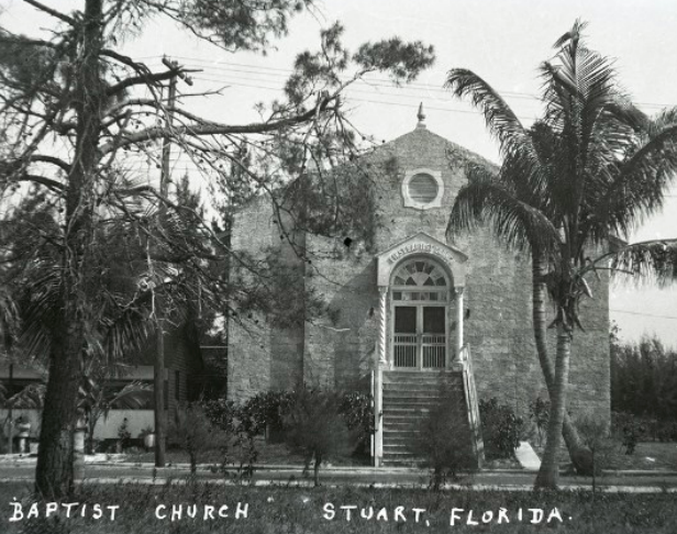 Baptist Church in Stuart, Florida. Old brick building with steps, trees, and a circular window above the entrance.